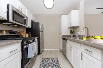 A kitchen with white cabinets and black appliances.